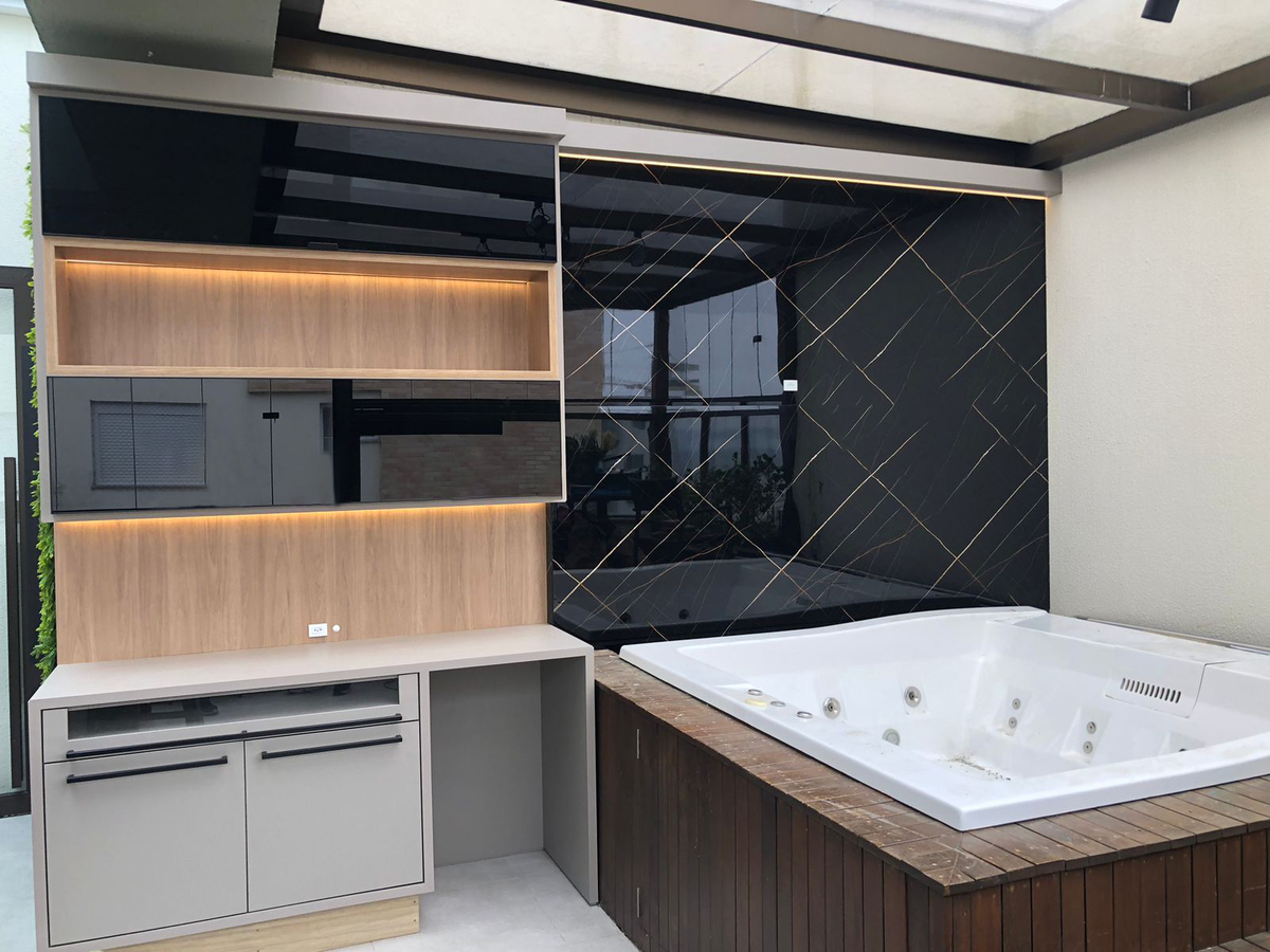 Banheiro elegante com revestimento de parede em porcelanato preto marmorizado com veios dourados, móvel planejado amadeirado com nichos iluminados, banheira de hidromassagem em deck de madeira, ambiente sofisticado, fotografia de interiores realista